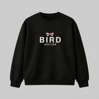 Mauve ribbon bow graphic on a black heavyweight sweatshirt. 350gsm organic ringspun cotton crewneck featuring BIRD VECTOR minimalist text branding.